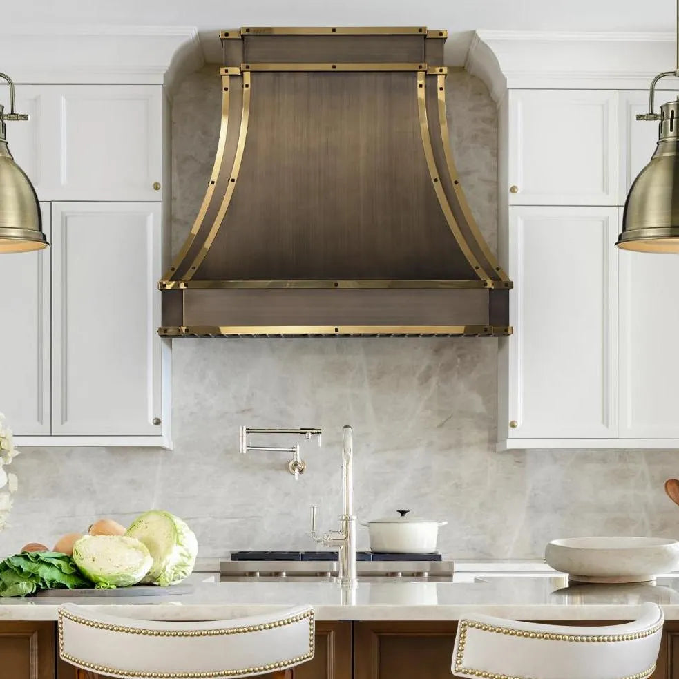 Antique brass range hood cover above a kitchen range