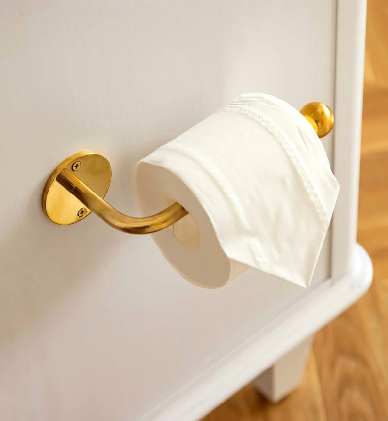 Vintage unlacquered brass toilet paper holder on a bathroom wall