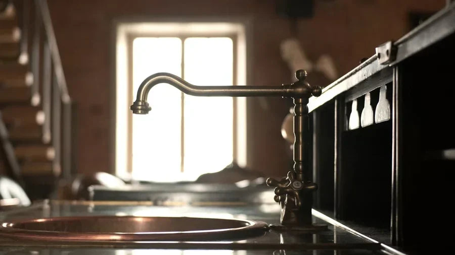Elegant brass faucet with vintage sink in rustic kitchen setting during afternoon light