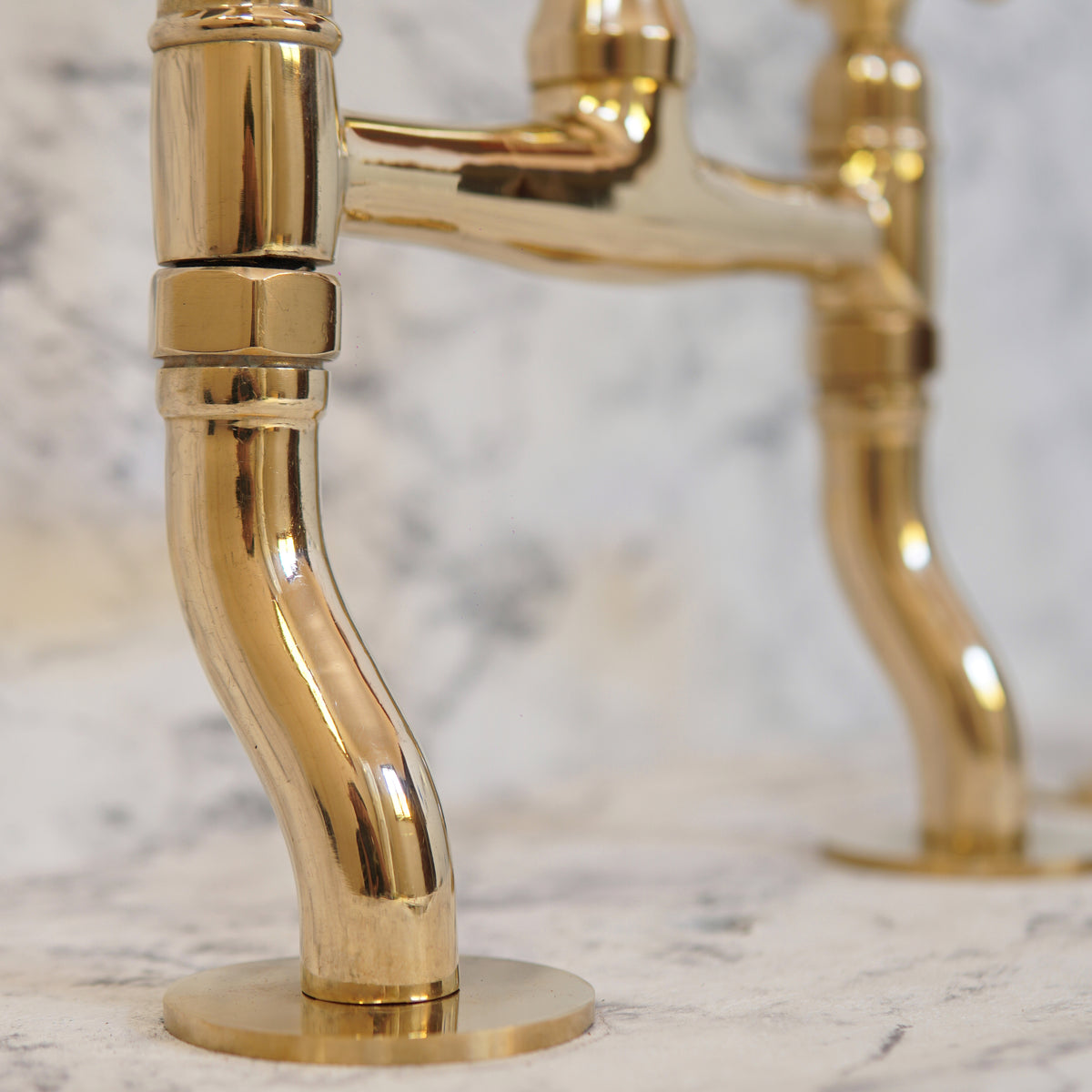 Unlacquered brass bridge kitchen faucet with graceful curved legs